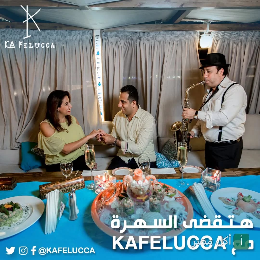 زوجان يحتفلان في مطعم الفلوكة بالجيزة مع عازف ساكسفون وأطباق مأكولات بحرية على الطاولة.