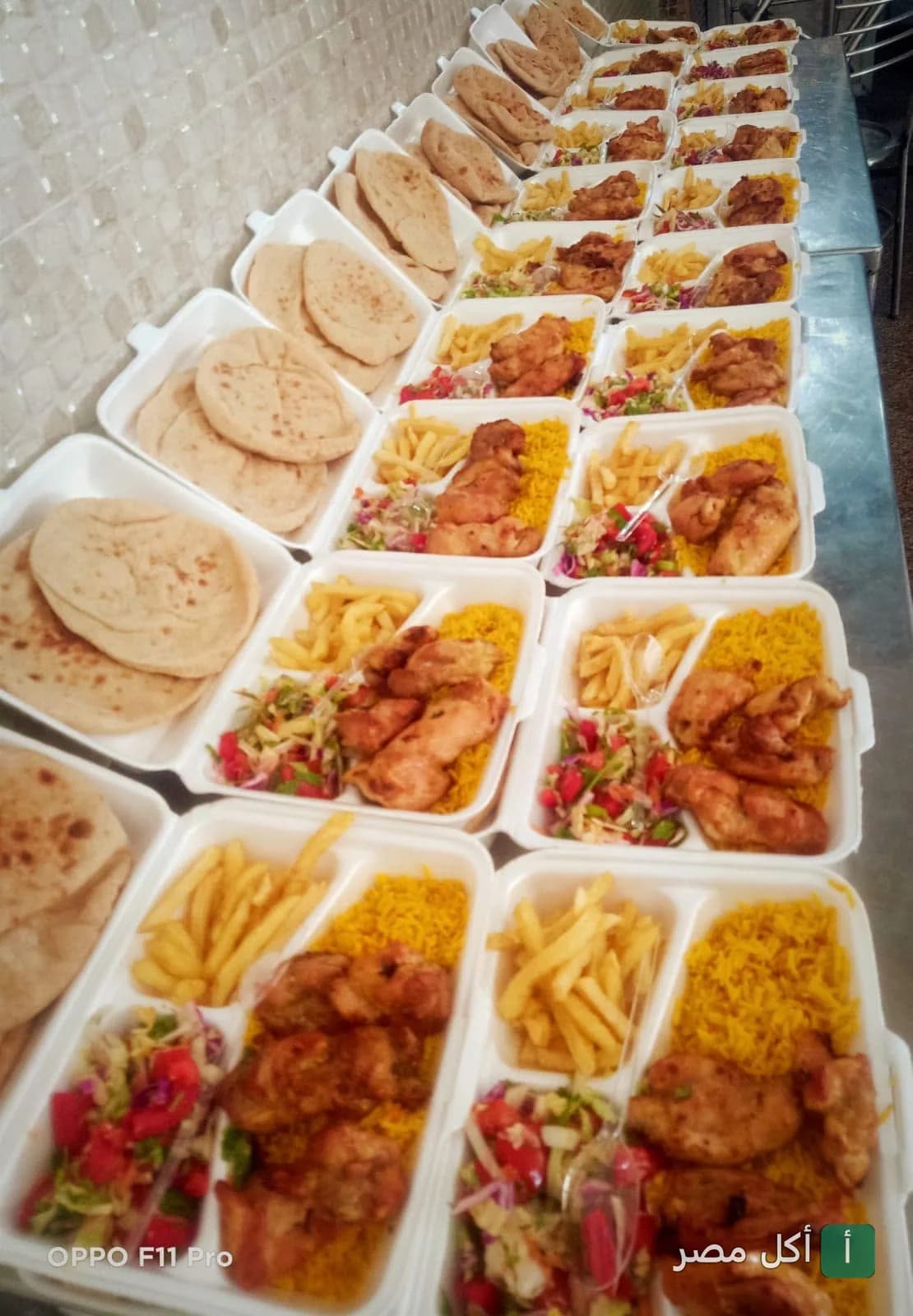 وجبات مشاوي جاهزة في علب مقسمة تحتوي على أرز أصفر، دجاج مشوي، بطاطس مقلية وسلطة مع خبز بلدي من مطعم الطاهر بفيصل