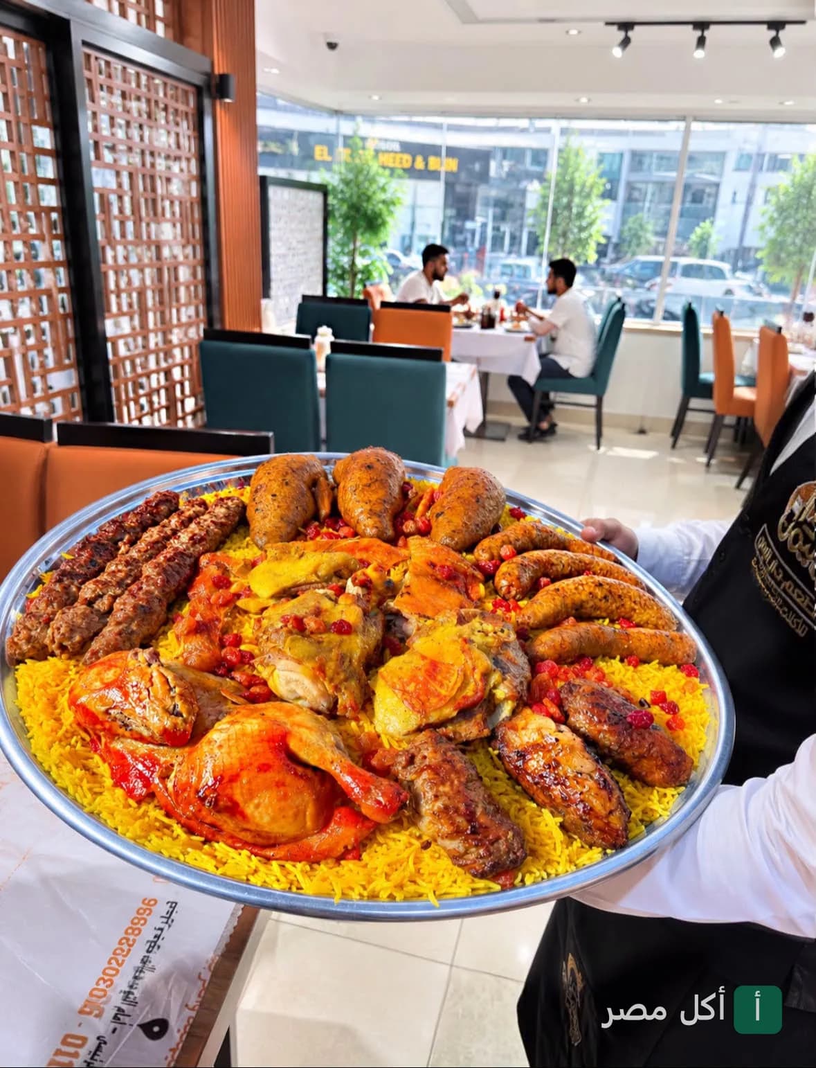 نادل يقدم صينية كبيرة من الأرز الشرقي مع المشويات والدجاج في مطعم دار اليمن بفيصل، الجيزة.