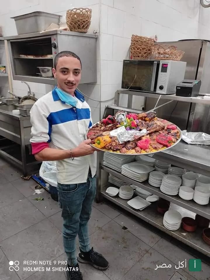موظف مطعم هالو في الجيزة يحمل صينية مشاوي مشكلة داخل مطبخ المطعم.