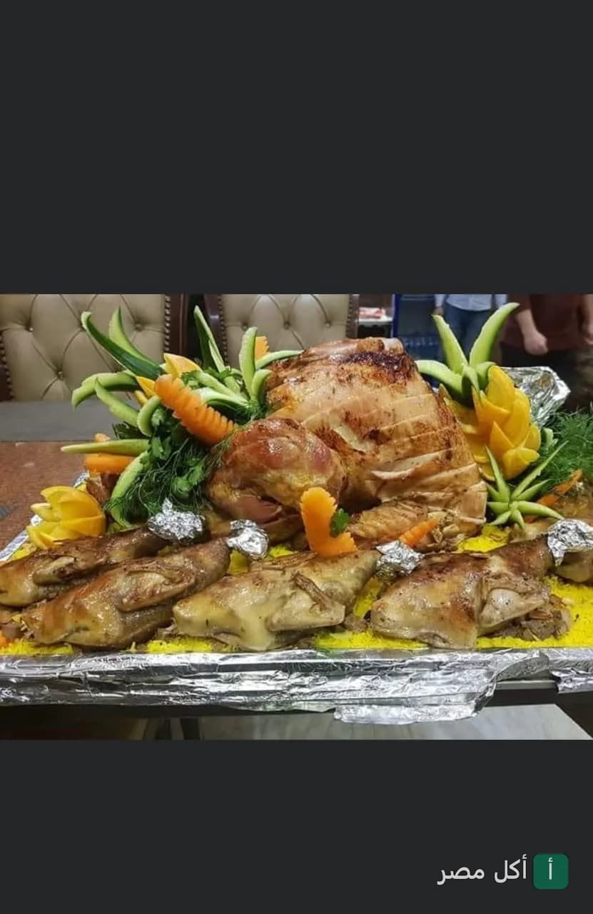 طبق مشاوي كبير من مطعم هالو في الجيزة، يضم دجاج محمر وخضروات مزينة.