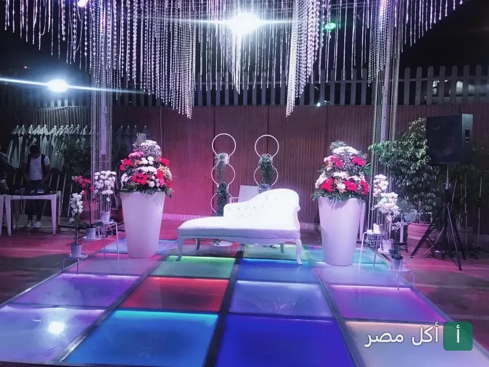 ديكور حفل زفاف أو مناسبة خاصة في مطعم سما لبنان بالجيزة مع إضاءة ملونة وأريكة بيضاء.