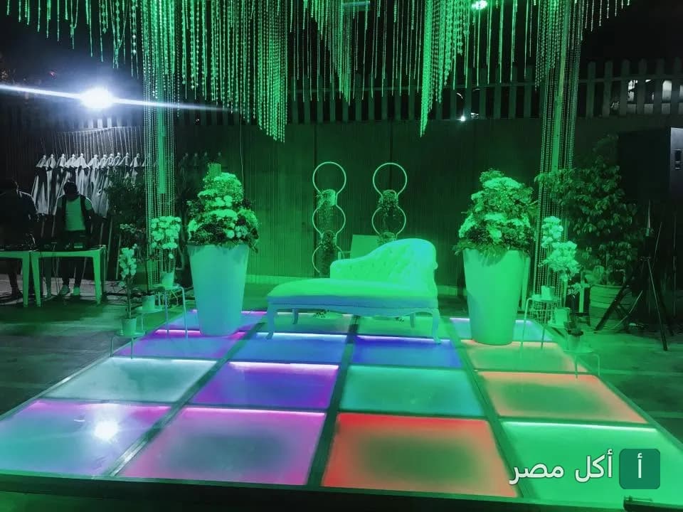 ديكور خارجي في مطعم سما لبنان بالجيزة يضم أريكة بيضاء على منصة مضيئة بإضاءة ملونة.