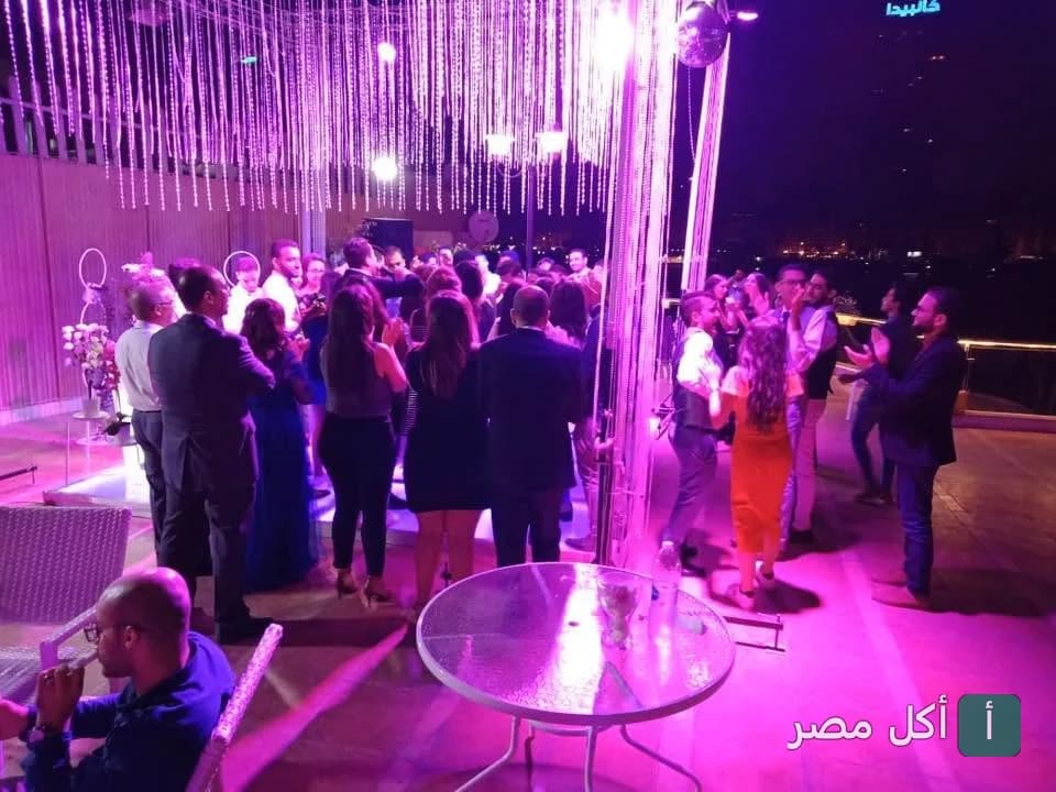أجواء احتفالية في مطعم سما لبنان بالجيزة مع إضاءة بنفسجية وديكورات متدلية.