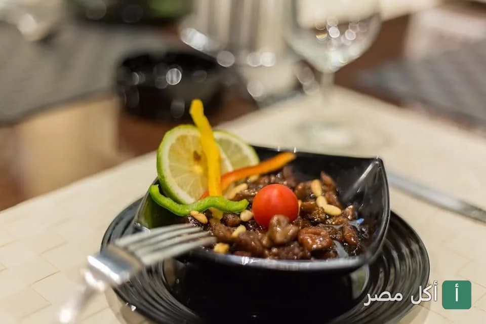 طبق مقبلات لبناني بقطع اللحم والصنوبر مزين بالليمون والفلفل في مطعم سما لبنان بالجيزة.