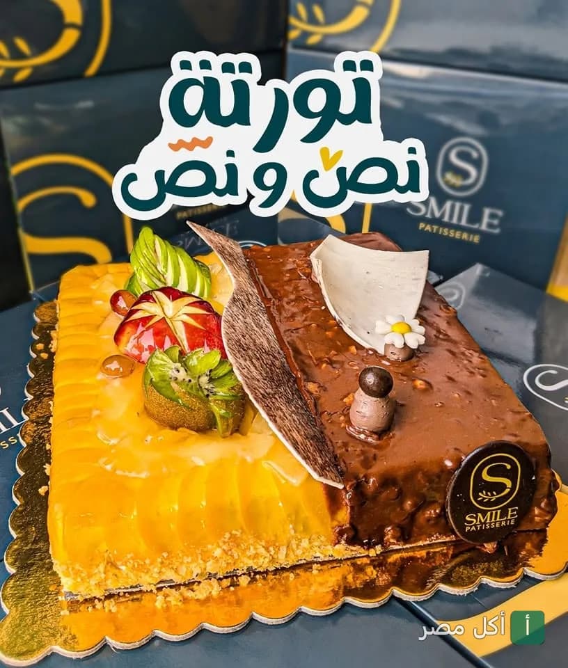 تورتة نص ونص من حلواني سمايل بشتيل مزينة بقطع الفاكهة والشوكولاتة.