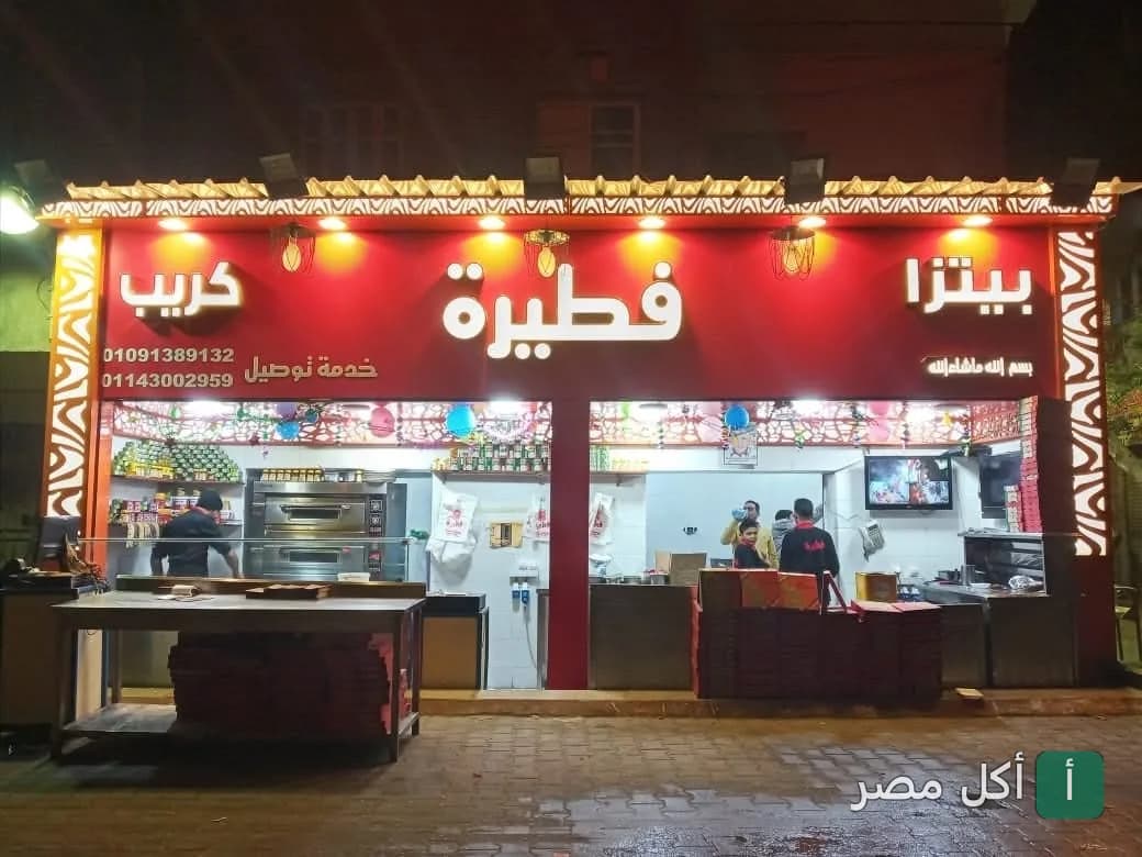 واجهة مطعم فطيرة في المنيرة بإمبابة، يظهر اسم المطعم باللون الأبيض على خلفية حمراء مضيئة.