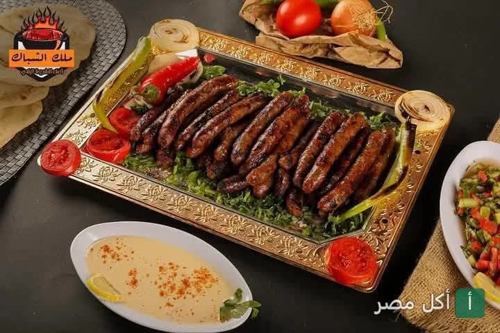 طبق سجق مشوي على الفحم مع سلطة طحينة وخضروات في مطعم مشويات ملك الشباك بإمبابة