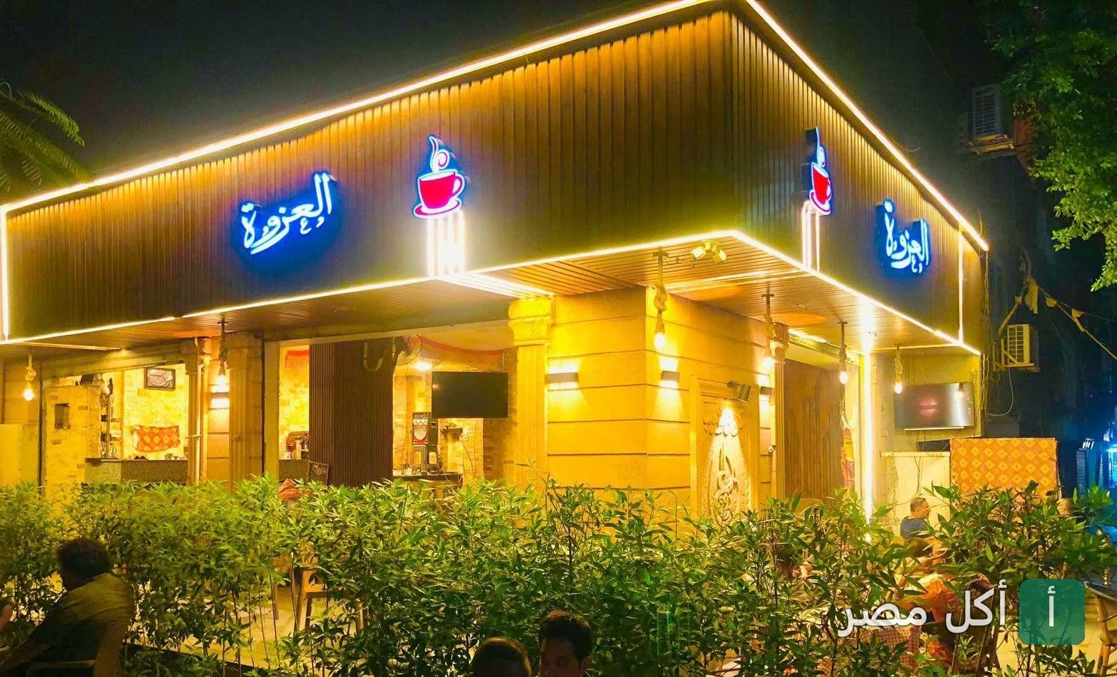 واجهة العزوة كافيه المضيئة ليلاً في مدينة العمال بإمبابة.