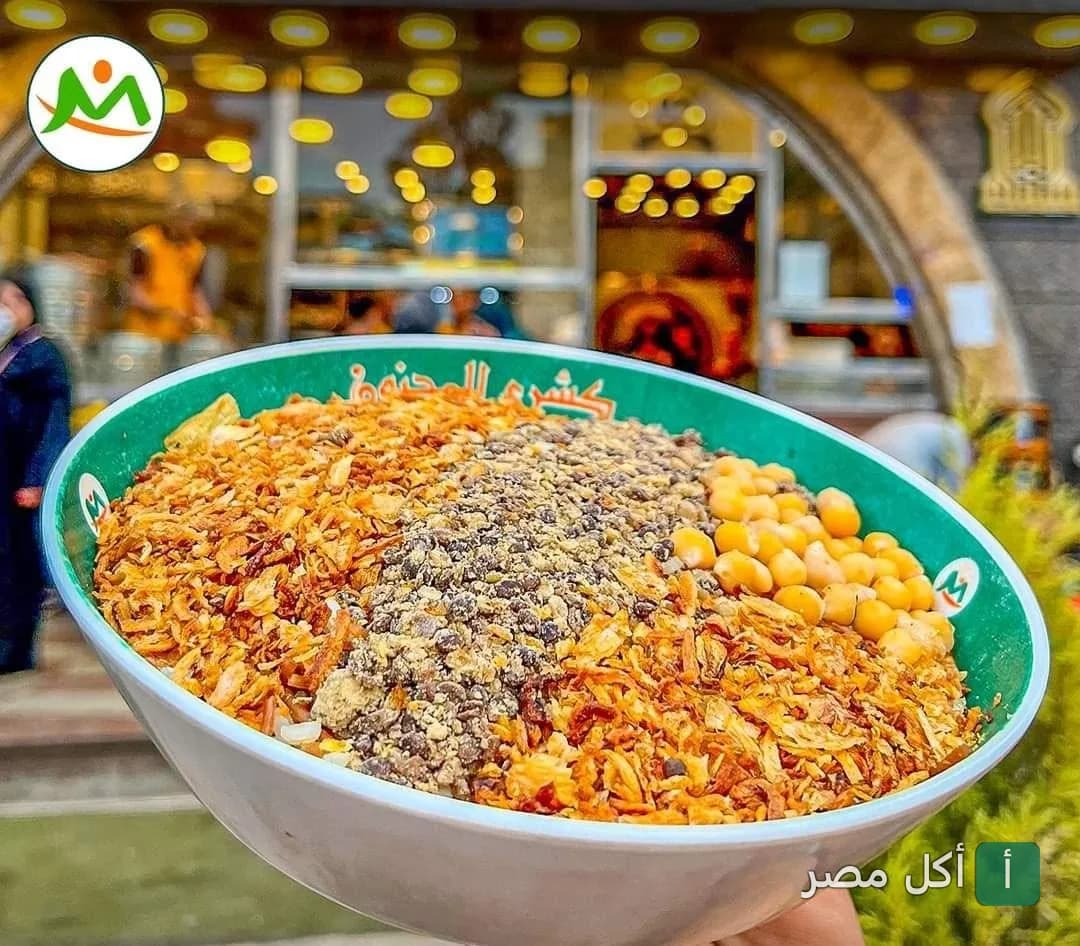 طبق كشري مصري أصيل من مطعم كشري المجنون في إمبابة، يظهر فيه العدس والحمص والبصل المقرمش.