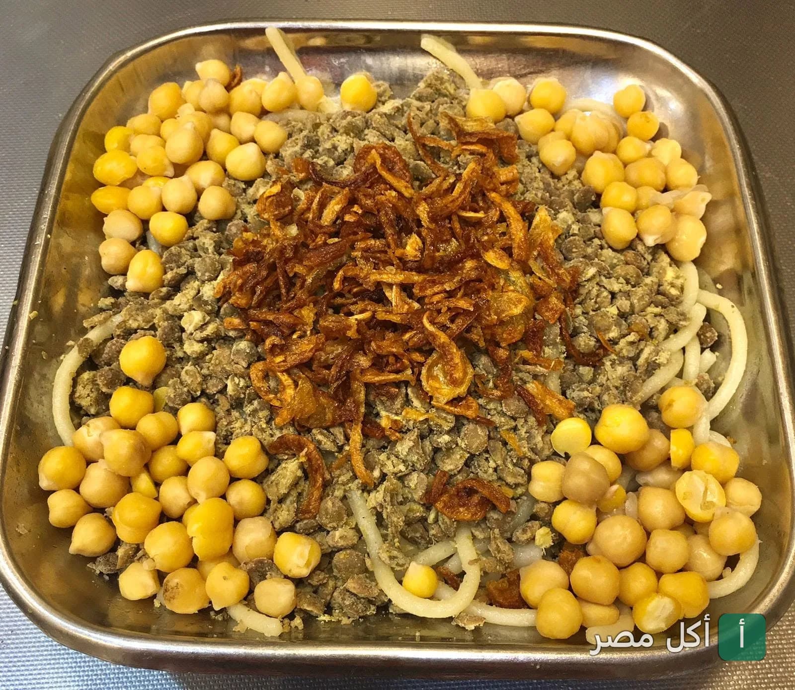 طبق كشري مصري تقليدي مغطى بالحمص والبصل المقرمش في مطعم كشري ابو عواد بالمنيرة، إمبابة.