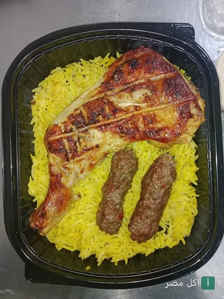 وجبة مشاوي من كبابجي سرور في إمبابة، تتكون من قطعة دجاج مشوي وكفتة مع أرز أصفر في علبة تيك أواي.