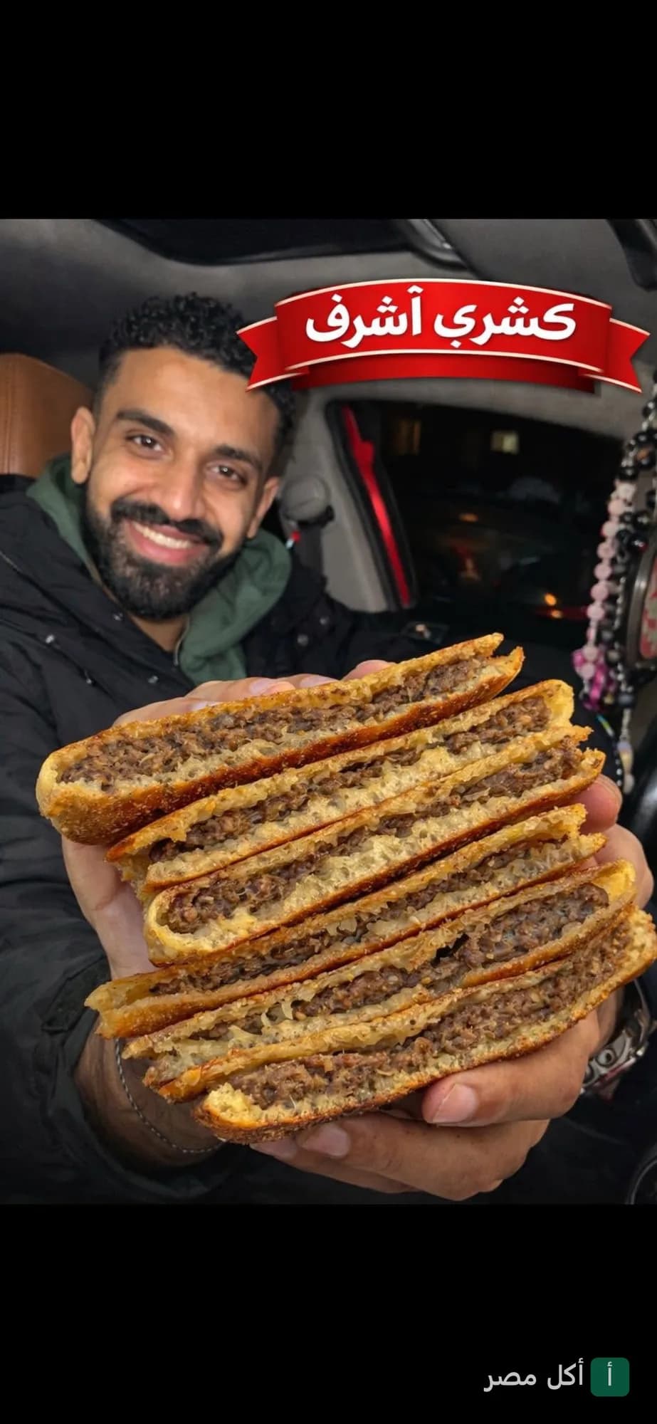 شخص يحمل شرائح حواوشي في كشري أشرف بشتيل بالوراق