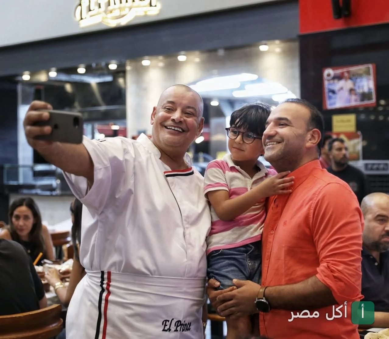شيف مطعم البرنس يلتقط صورة سيلفي مع زبائن داخل المطعم.