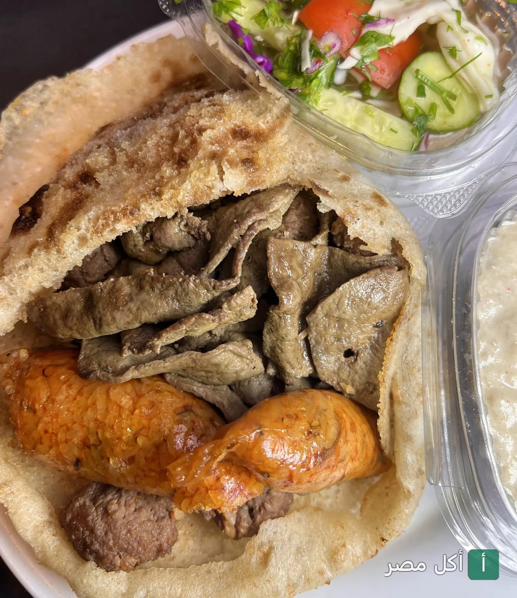 ساندوتش مشويات من بيبو'ز جريل في إمبابة، يحتوي على كبدة وسجق في خبز بلدي مع سلطة خضراء وطحينة.