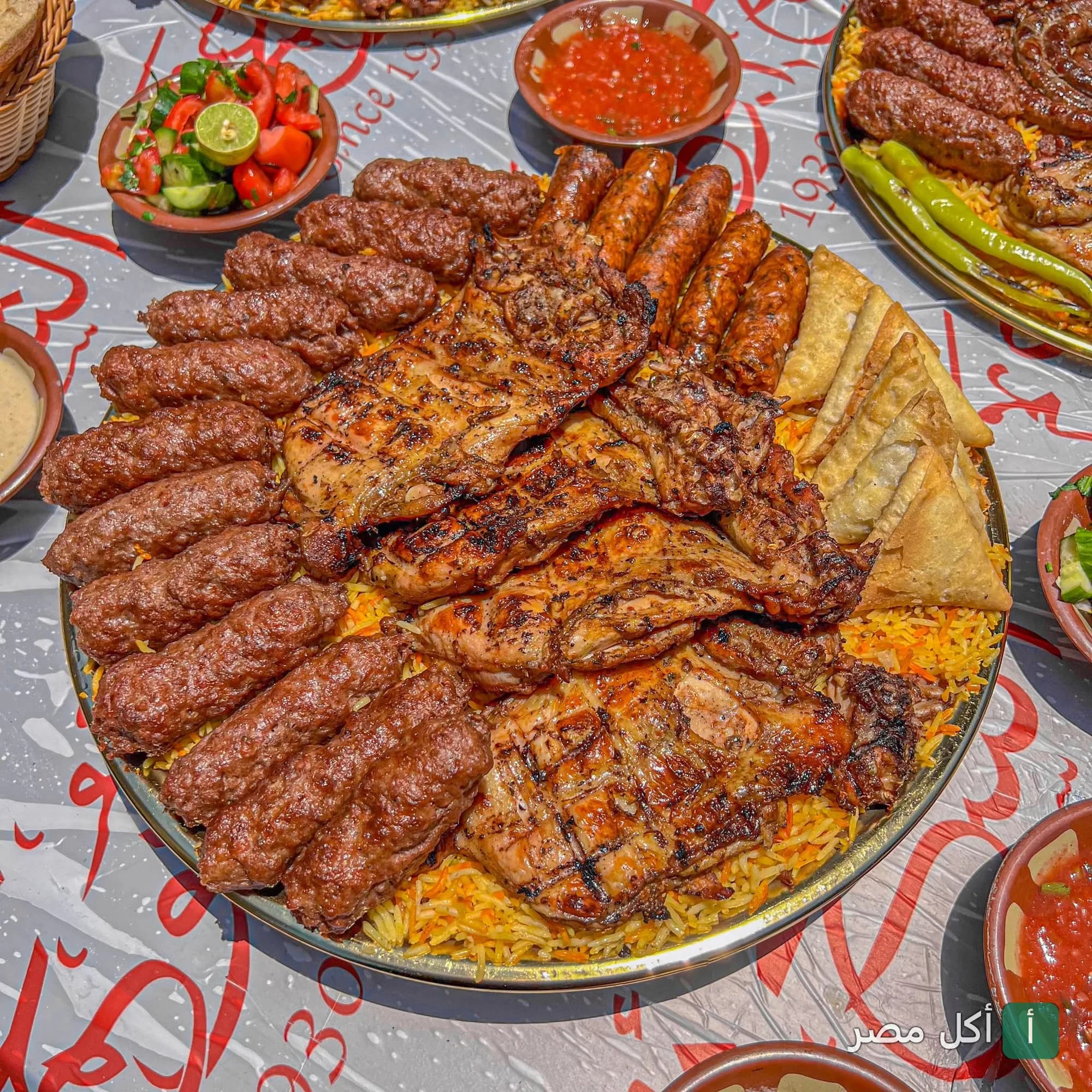 صينية مشويات مشكلة تضم كفتة ودجاج مشوي وسمبوسك على أرز أصفر في مطعم مشويات الشيخ أبو عمر بالصف.