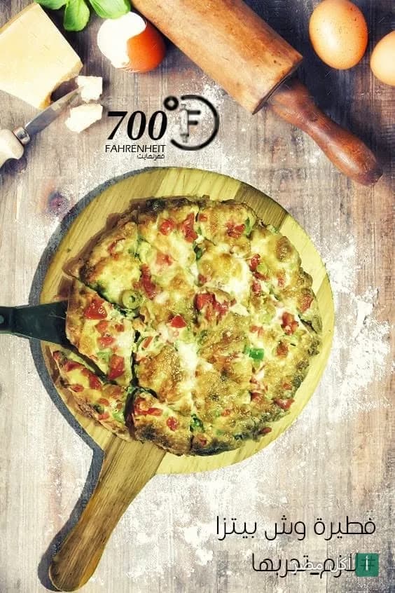 بيتزا طازجة على لوح خشبي في مطعم 700 فهرنهايت بالصف، مع أدوات تحضير العجين.