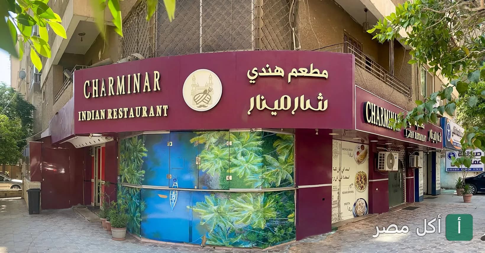 واجهة مطعم شارمينار الهندي في الصف، تظهر لافتة المطعم باللون العنابي مع رسومات استوائية.