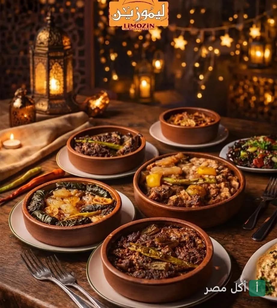 طاولة طعام تحتوي على طواجن شرقية متنوعة في مطعم ليموزين بالصف، مع إضاءة دافئة وفوانيس.