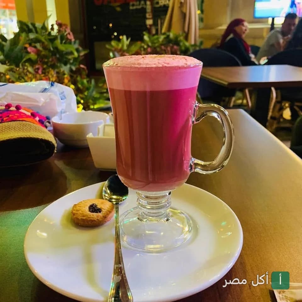 كوب مشروب ساخن وردي اللون مع قطعة بسكويت صغيرة في مطعم كاسكادا بالصف
