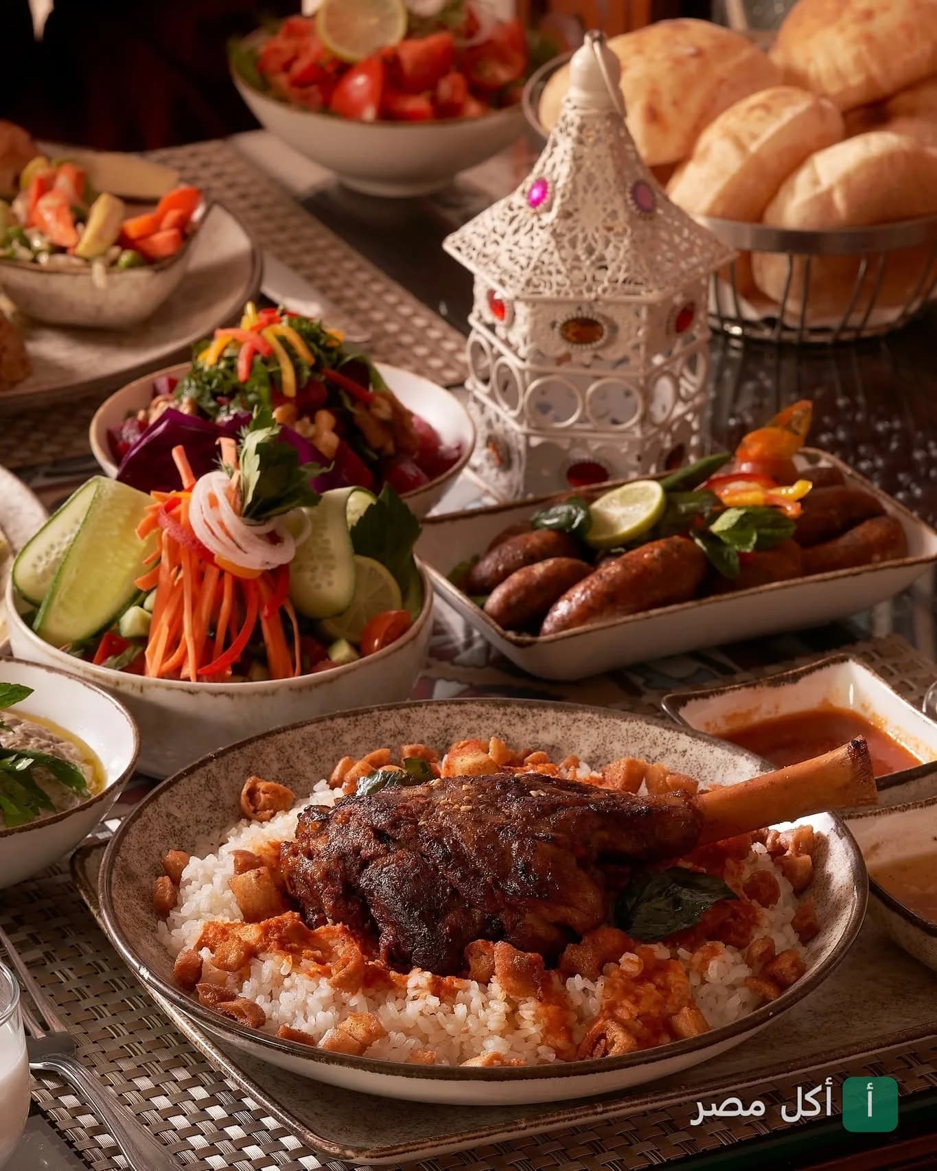 مائدة شرقية متنوعة في مطعم الخديوي تضم طبق موزة ضاني مع الأرز، سلطات طازجة، ومقبلات، مع فانوس رمضاني.