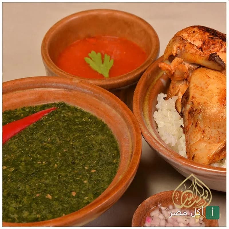 أطباق شرقية تقليدية من مطعم أبو السيد تشمل ملوخية ودجاج مشوي مع أرز في أواني فخارية.