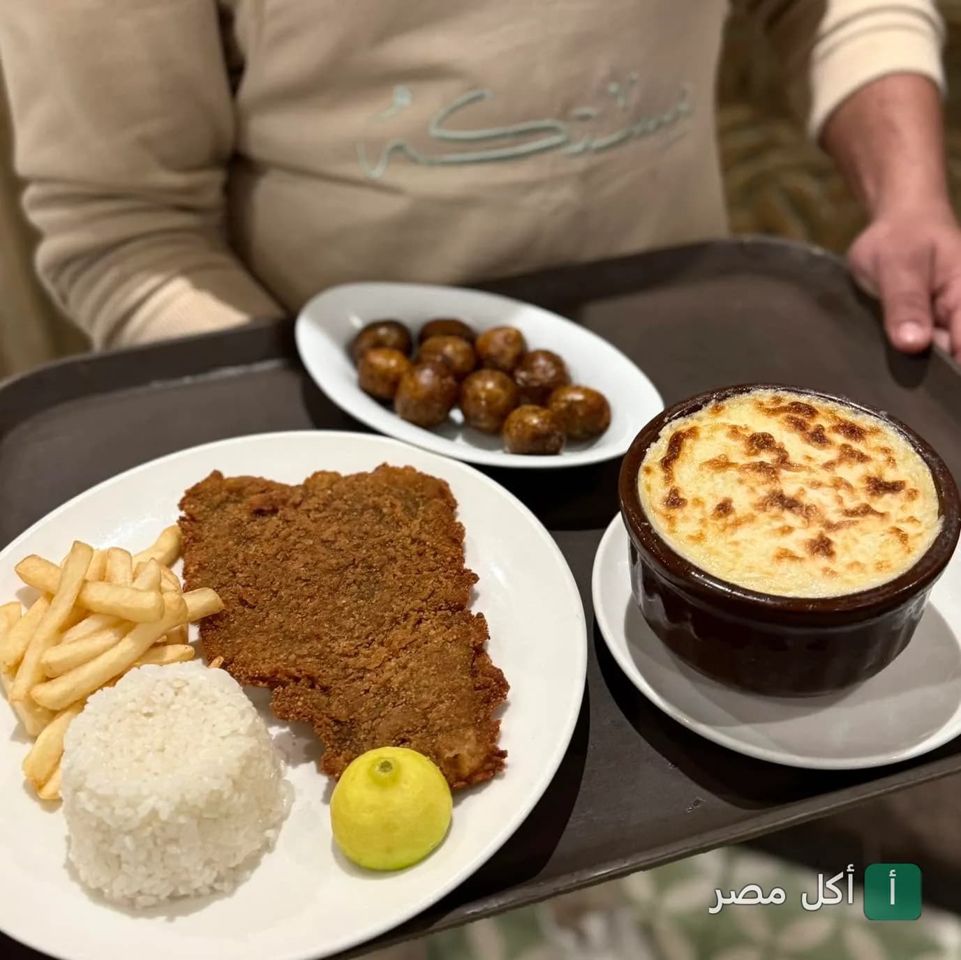 صينية تقديم تحتوي على طبق بانيه مع أرز وبطاطس وطاجن بالبشاميل في برنسيس كافيه بوينت 6 مول بالشيخ زايد.