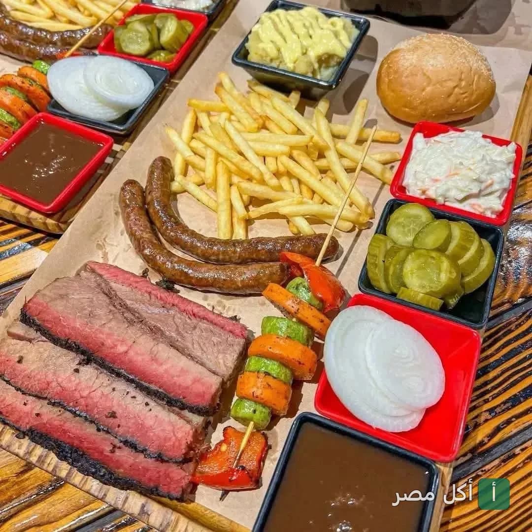 وجبة مشاوي متنوعة من مطعم دراجوز في بارك أفينيو بالشيخ زايد، تضم شرائح بريسكت، نقانق، خضار مشوي، وبطاطس مقلية.