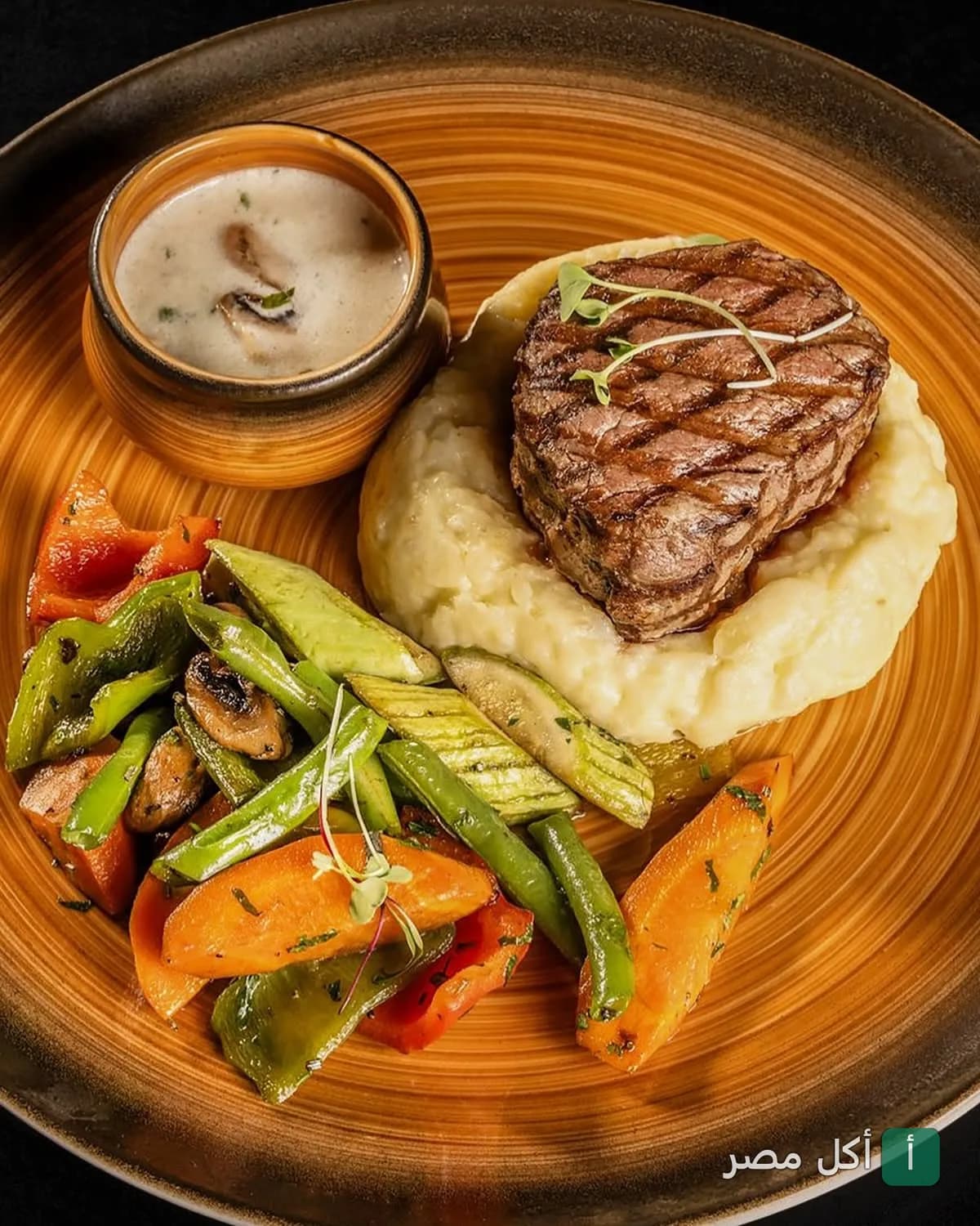 طبق ستيك مشوي مع بطاطس مهروسة وخضار سوتيه وصوص مشروم في مطعم SAL Restaurants بالشيخ زايد.