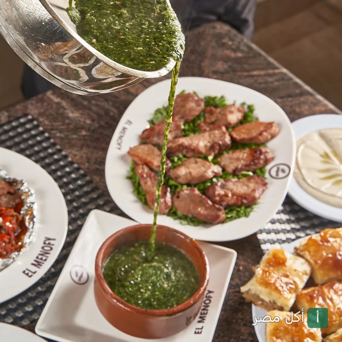 صب طشة الملوخية الساخنة في طاجن فخار بمطعم الكبابجي المنوفي في الشيخ زايد مع أطباق المشاوي.