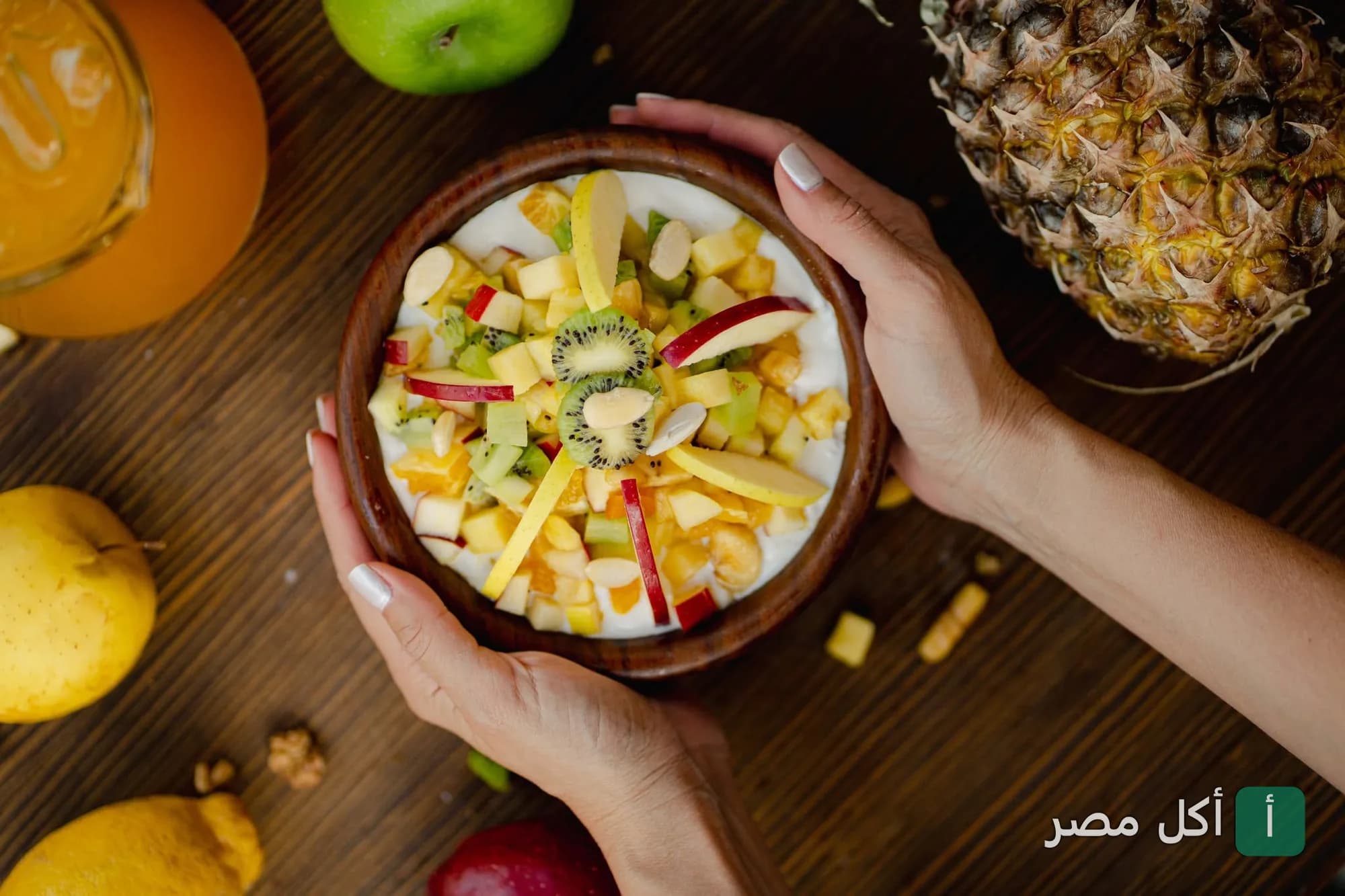 يدان تحملان وعاء خشبي به زبادي وفواكه مقطعة مثل الكيوي والتفاح في مطعم كاسا دي فريدة بالشيخ زايد.