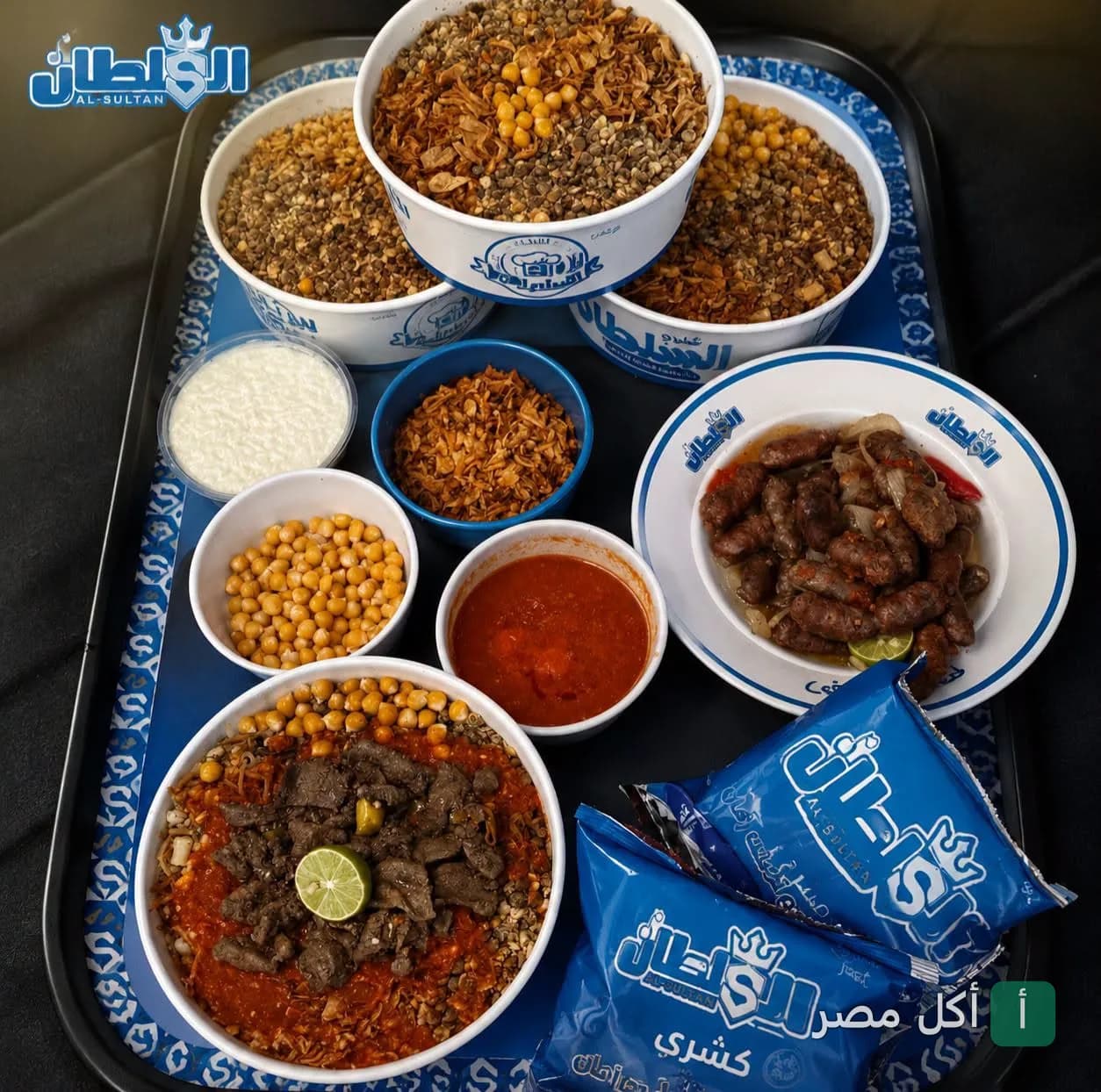 صينية تحتوي على أطباق كشري متنوعة مع إضافات مثل الكبدة والسجق من كشري السلطان بالوراق.