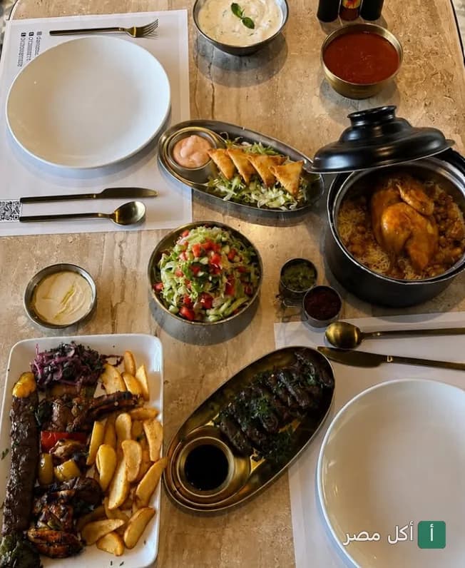 مائدة طعام متنوعة من مطعم دار نوره بالوراق، تضم أطباق مشويات ومقبلات ومحاشي.