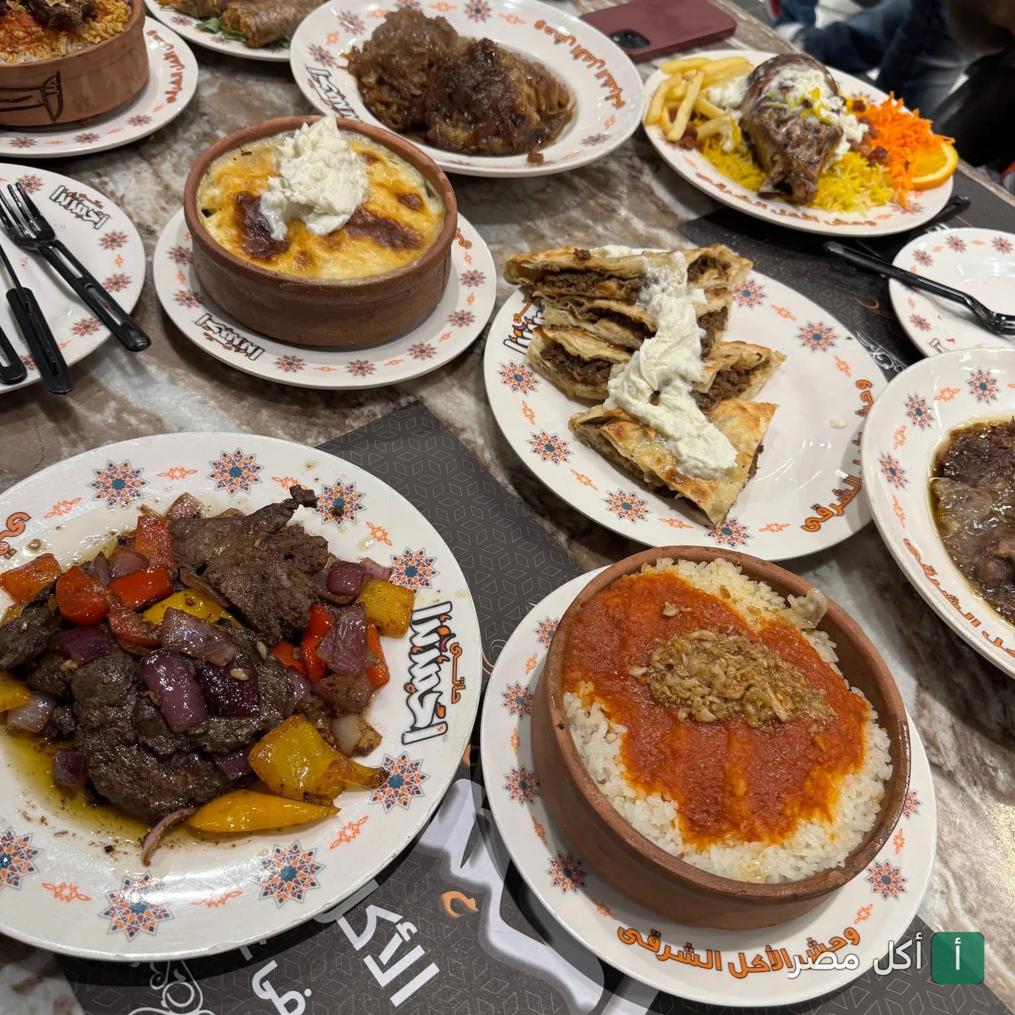 مائدة متنوعة من الأطباق المصرية التقليدية في مطعم أكل و بحلقة بالوراق، تشمل طواجن أرز بالصلصة، لحم مشوي، وفطائر.