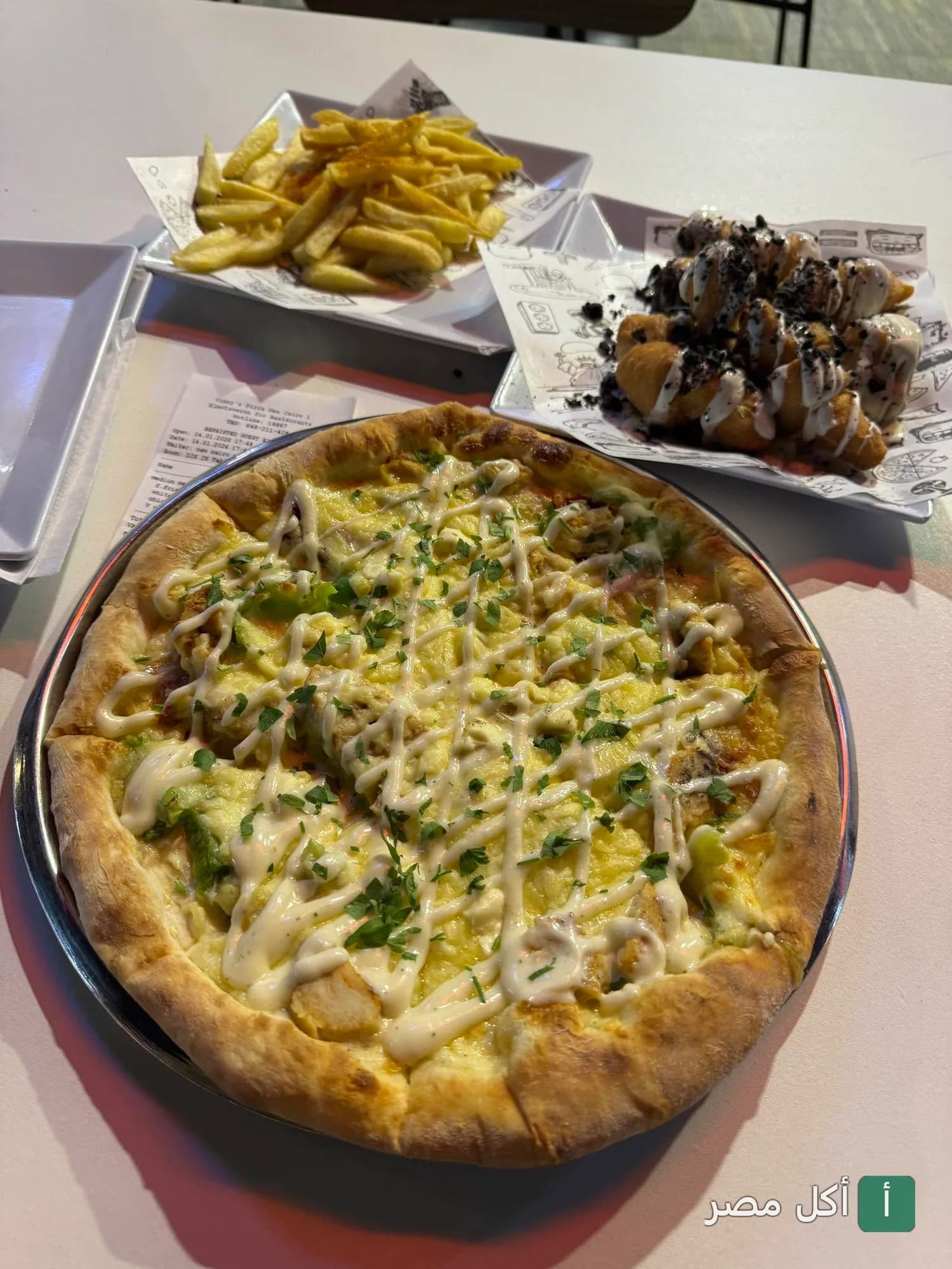 بيتزا بالدجاج مع صوص أبيض، بطاطس مقلية، وحلوى مغطاة بقطع الشوكولاتة في مطعم أكل و بحلقة بالوراق.
