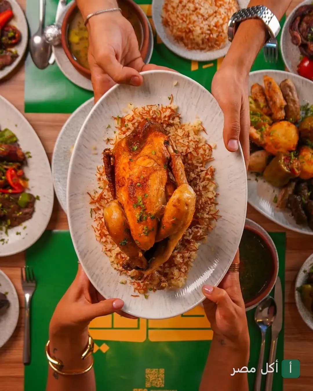 طبق دجاج محمر مع أرز بالشعيرية يتم تقديمه على مائدة مليئة بأطباق المحاشي في مطعم محشي ماما بالوراق.