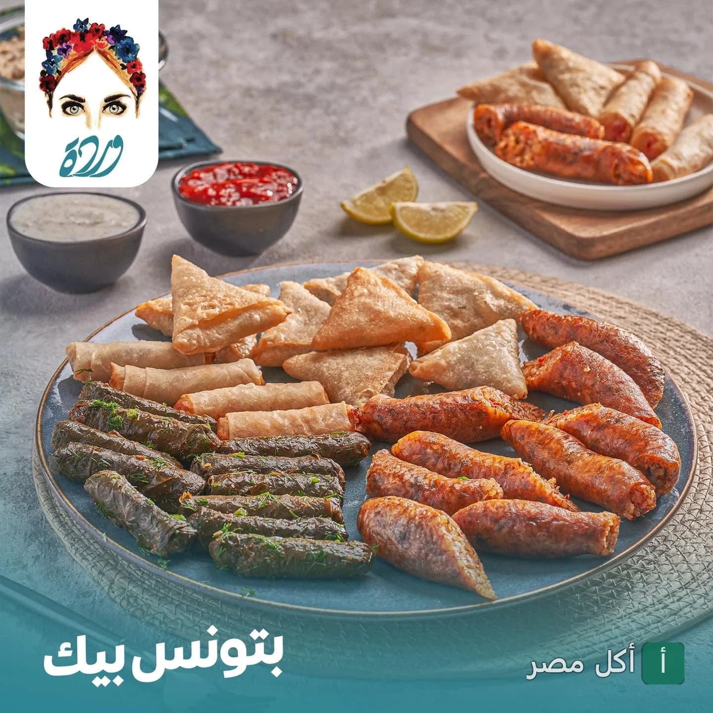 طبق مشكل من كافيه وردة بالوراق يحتوي على محشي ورق عنب، سمبوسك، وممبار محمر.