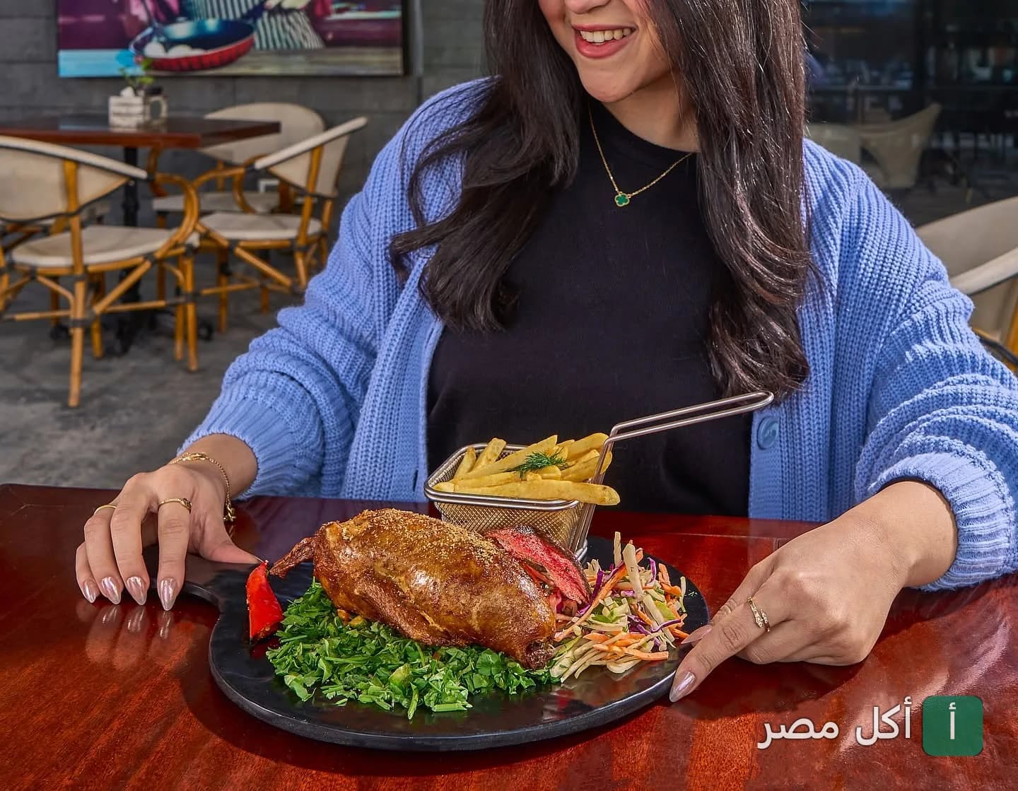 زبونة في مطعم بلكونة بالوراق تستمتع بوجبة حمام محشي مع بطاطس مقلية وسلطة.