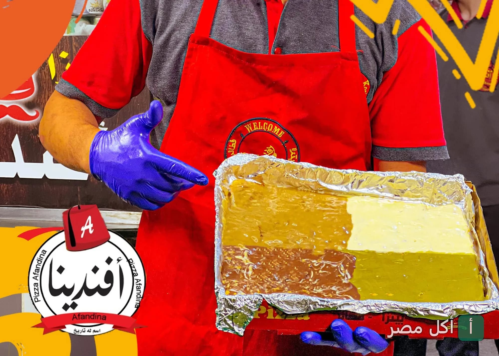 موظف مطعم افندينا بحدائق الأهرام يرتدي مريلة حمراء ويحمل صينية بيتزا متنوعة النكهات.