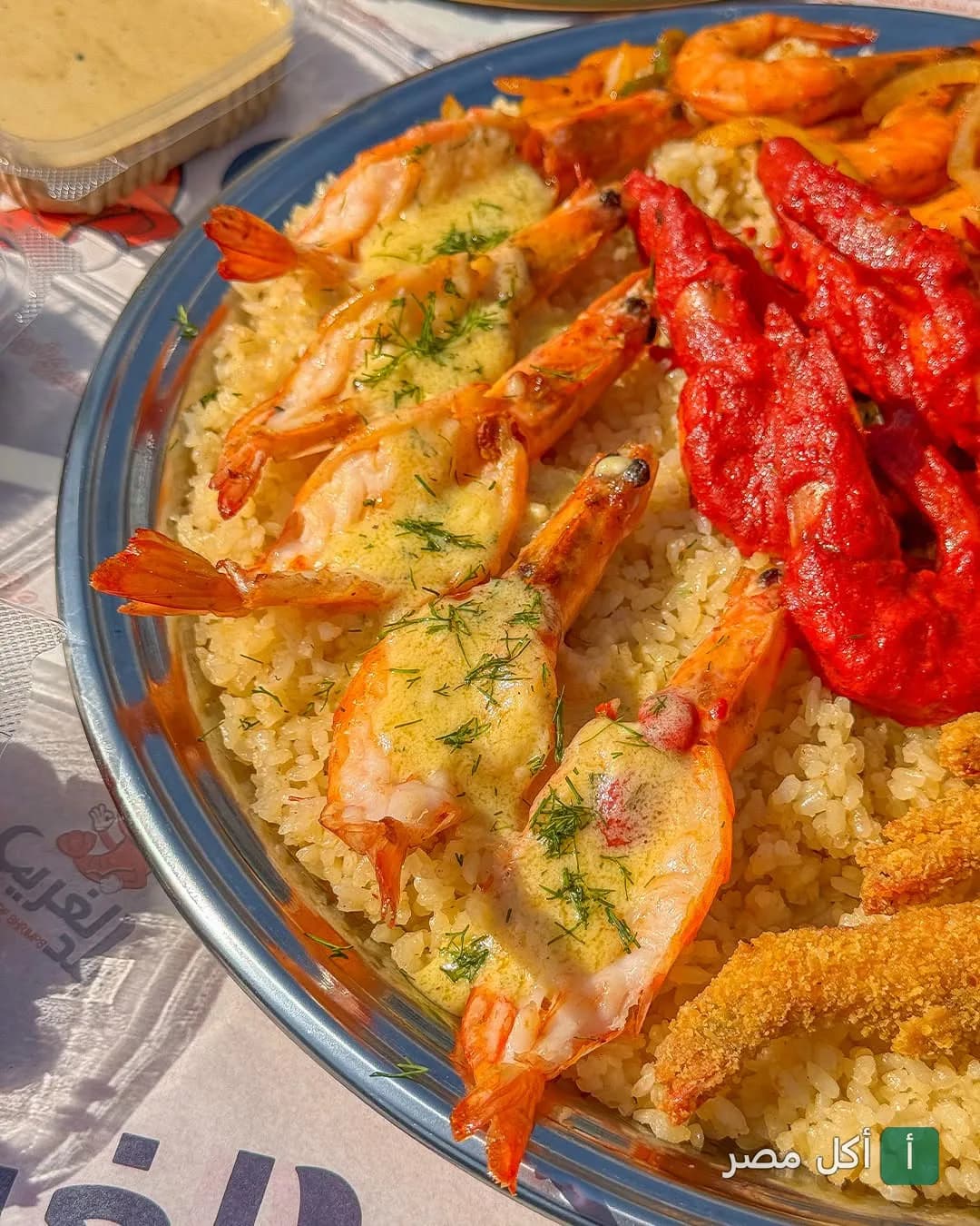 طبق مأكولات بحرية متنوع يضم جمبري مشوي بصوص الزبدة وجمبري مقلي على أرز في مطعم بلد الغريب بحدائق الأهرام.