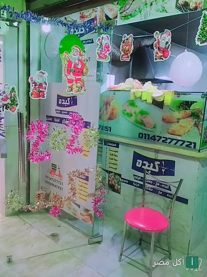 واجهة مطعم نص كبده في الأهرام مزينة بديكورات احتفالية وكرسي وردي أمام المحل.