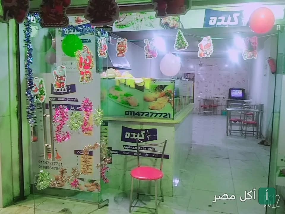 واجهة مطعم نص كبده في الأهرام، يظهر كراسي وطاولات داخل صالة الطعام مع زينة احتفالية.