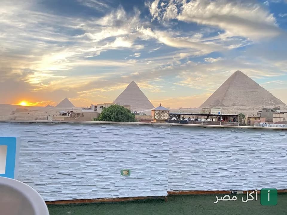 إطلالة بانورامية على أهرامات الجيزة وقت الغروب من تراس روكان كافيه في نزلة السمان.
