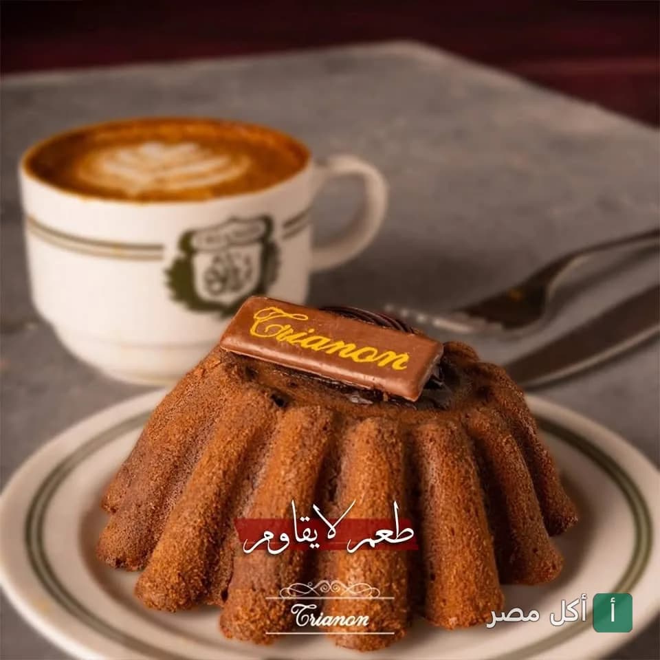 قطعة جاتوه شوكولاتة مزينة بشعار ترانون مع كوب قهوة في مطعم ترانون بالجيزة.