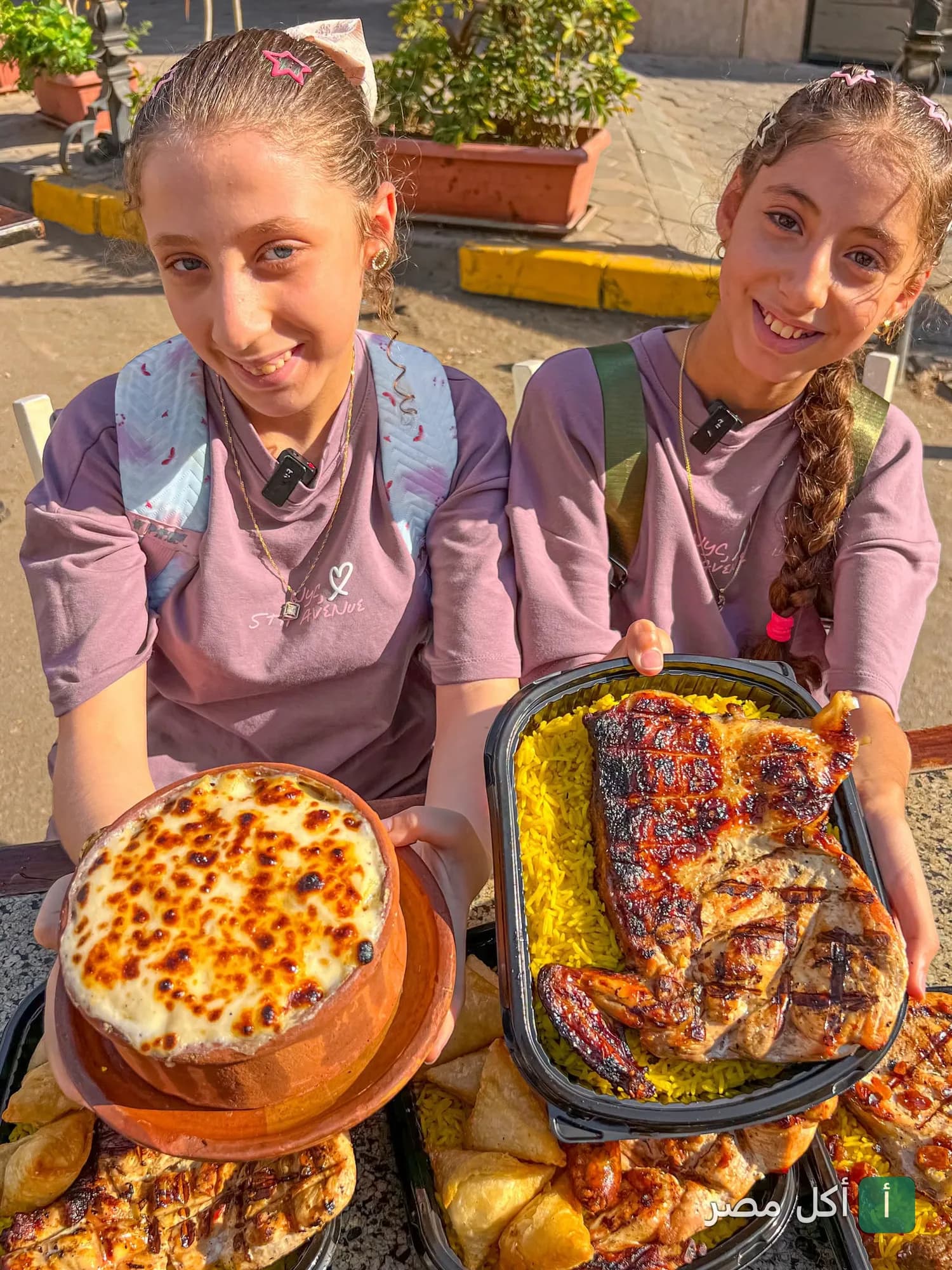 فتاتان تحملان طاجن بالبشاميل ودجاج مشوي مع أرز في مطعم دوار ام حسن بالدقي