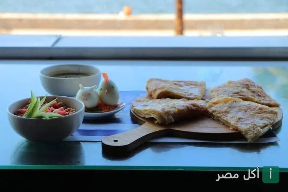فطير مشلتت مقطع على لوح خشبي مع أطباق جانبية في قهوة رامي بمدينة العمال في إمبابة.