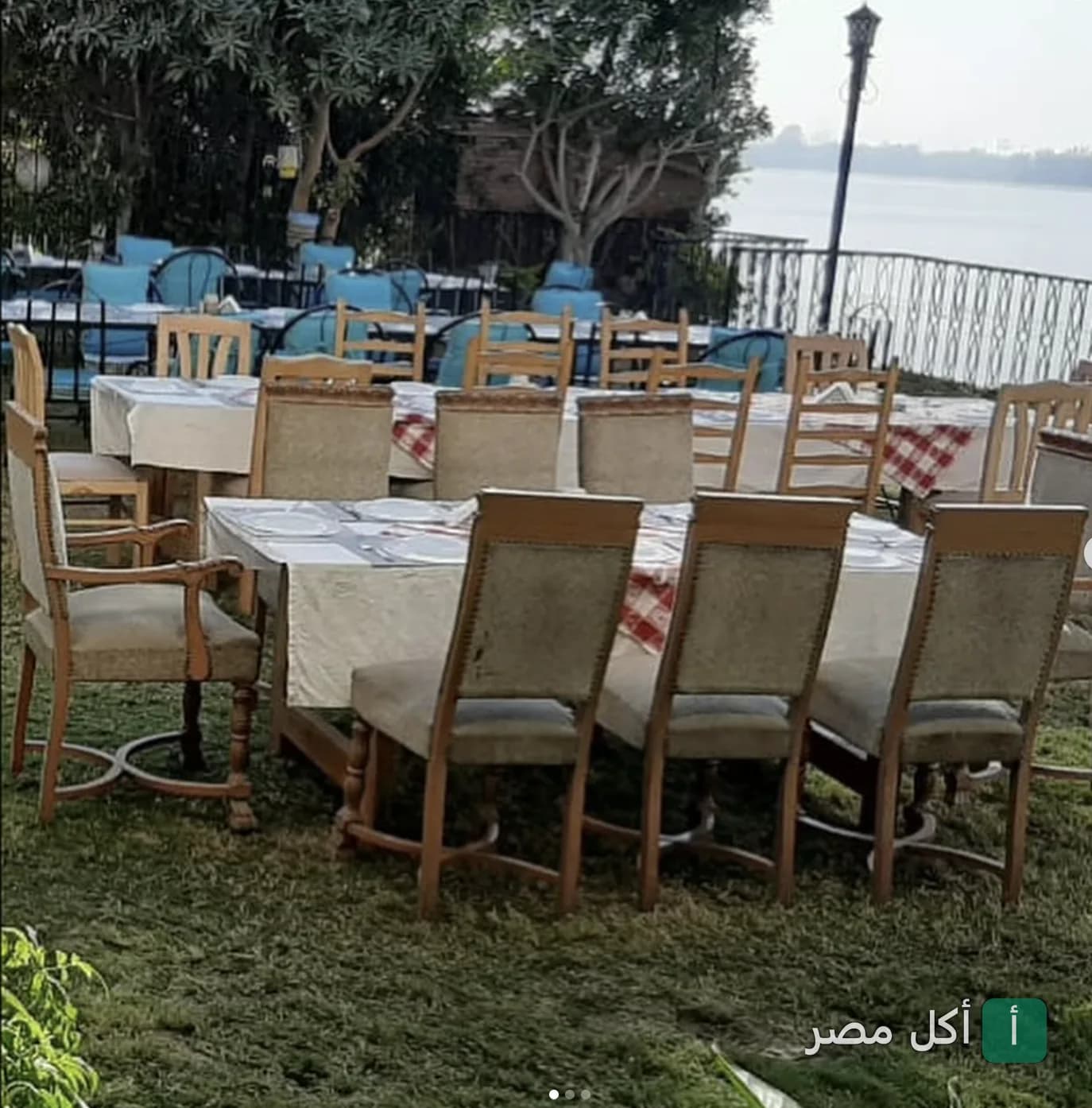جلسات خارجية في مطعم بيت عزيز مصر تطل على النيل مع طاولات مرتبة في مساحة خضراء.