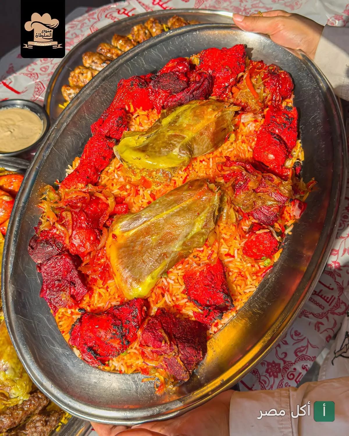 طبق مندي كبير من مطعم مندي السلطان بالصف، يقدم أرز المندي مع قطع الدجاج المشوي باللون الأحمر.