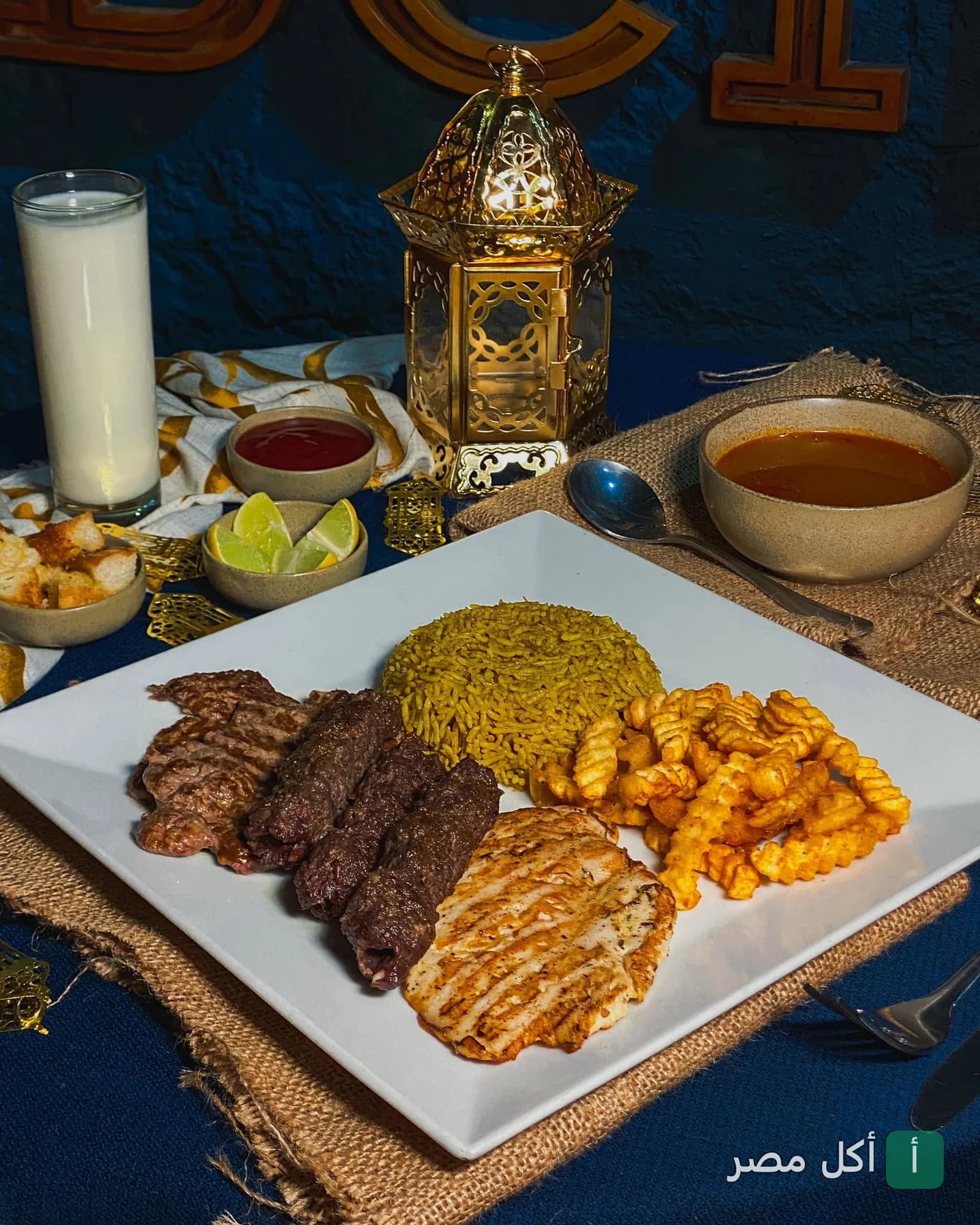 طبق مشويات متنوع من مطعم سينتو بيني في العطارين، يضم كفتة وقطع دجاج وأرز وبطاطس مقلية مع فانوس رمضان.