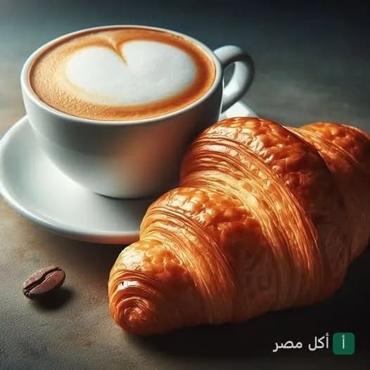 كوب قهوة برسمة قلب مع كرواسون طازج في مطعم لا جورمانديز بالإسكندرية.